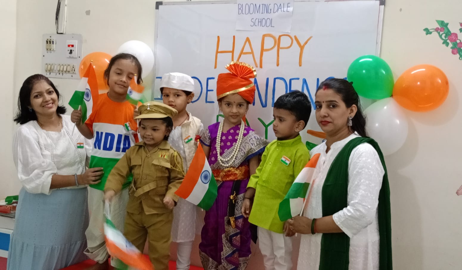 Children and teachers celebrating Independence Day with flags and costumes at Blooming Dale School